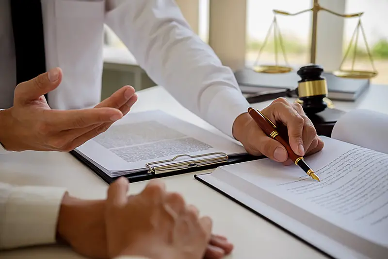 Justice and Law concept. Legal counsel presents to the client a signed contract with gavel and legal law or legal having team meeting at law firm in background