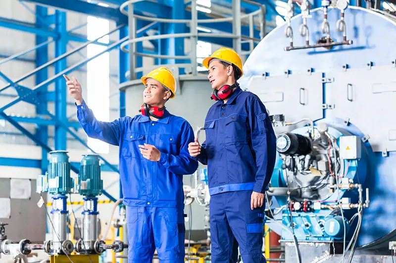 Two men in blue wearing safety hat inside the manufacturing plant