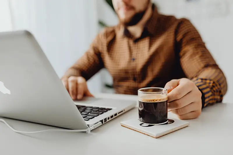 Man in brown shirt working in front of his laptop