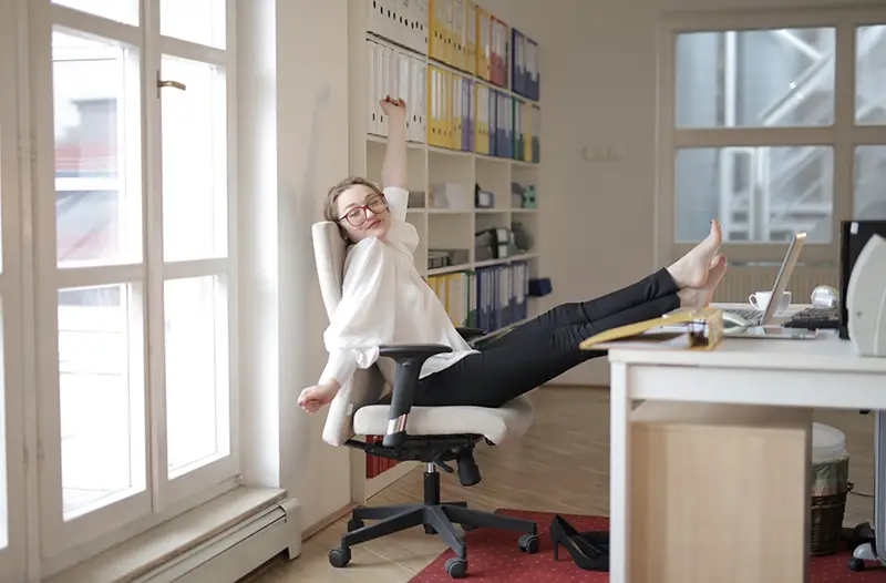 Female employee relaxing with feet on the table in office