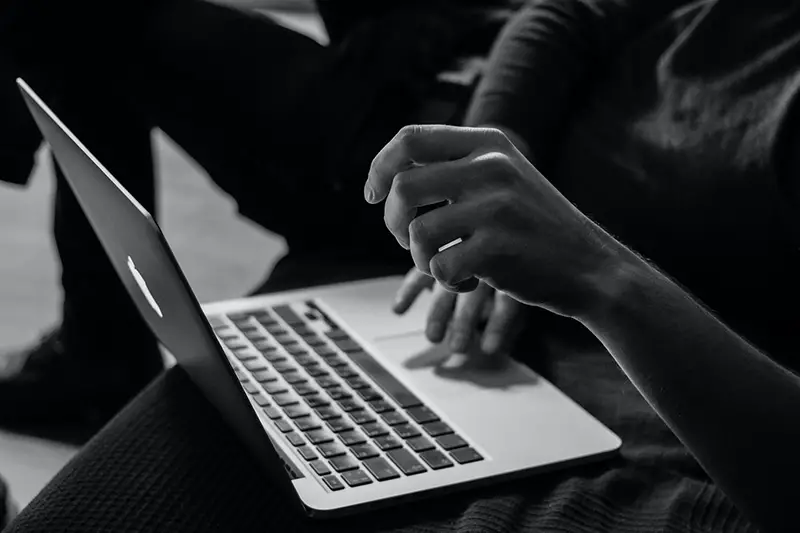Grayscale photo of a person using Macbook pro