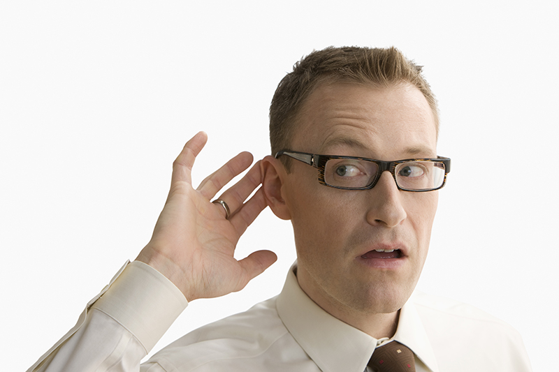 Man wearing eyeglasses putting his hand on his ear