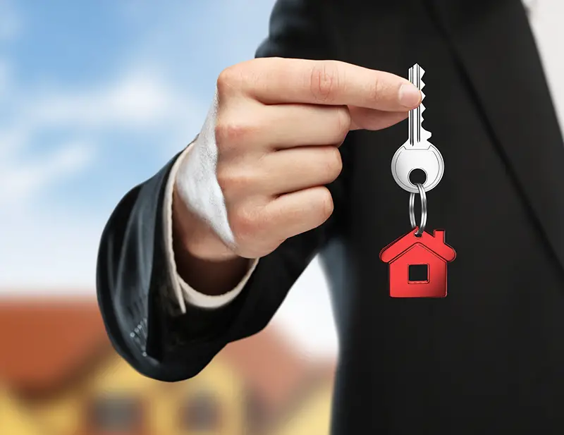 Man in black suit holding a house key
