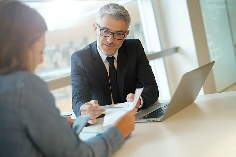 Woman in banker's office signing financial loan