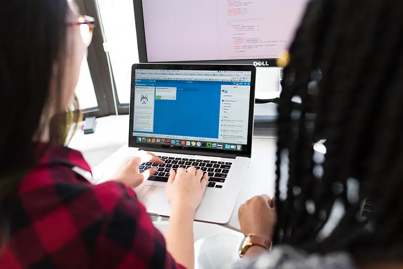 Two women using macbook pro