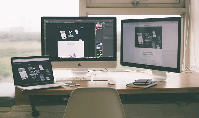 Two computer screens and a laptop on the table