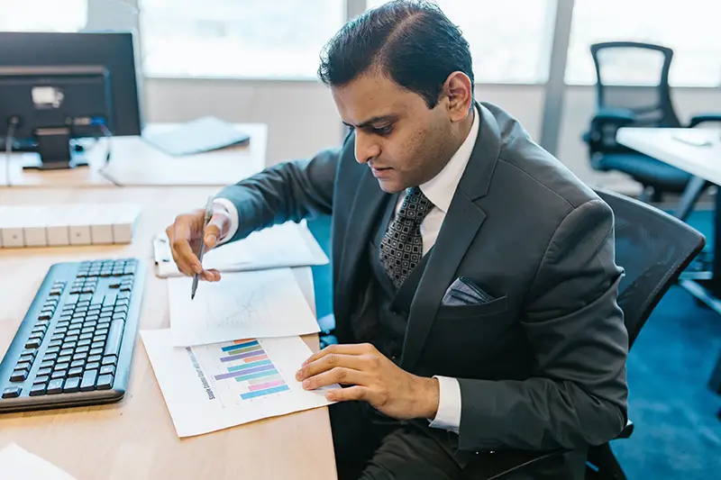 man in gray suit jacket writing on a paper