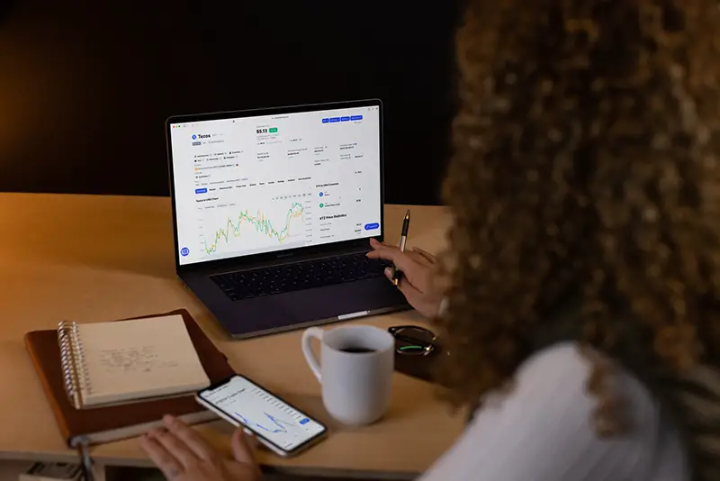 woman in front of computer with trading graph on screen