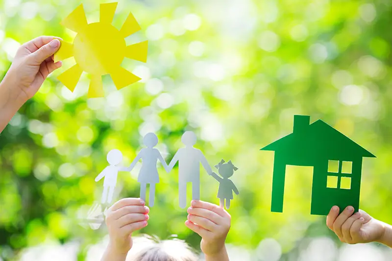 Ecology house and family in hands against spring green background