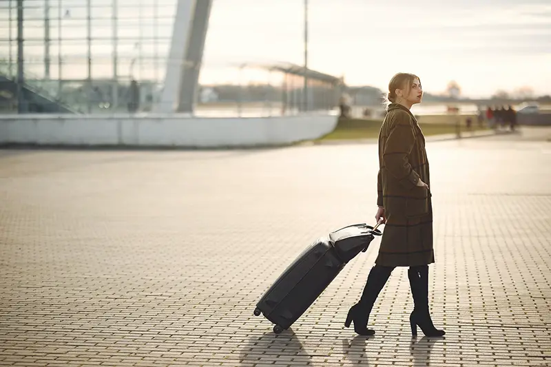 Woman walking on pavement with luggage