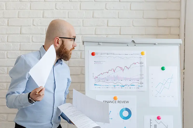 a man looking at charts and graphs on a white board