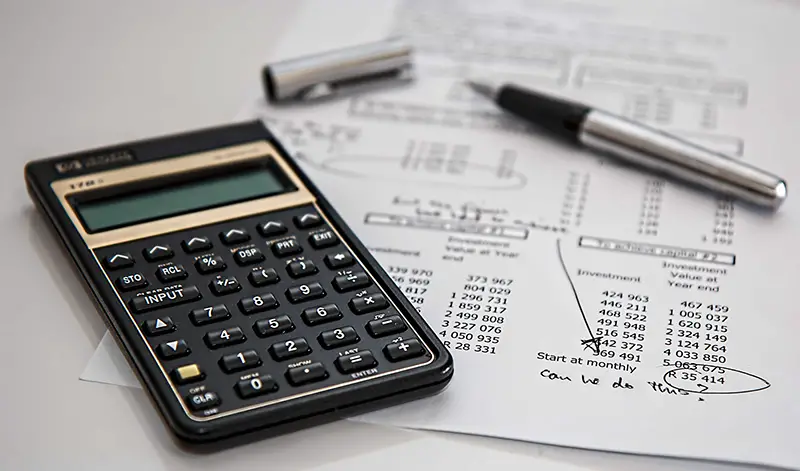 Black calculator and silver pen on the top of white paper