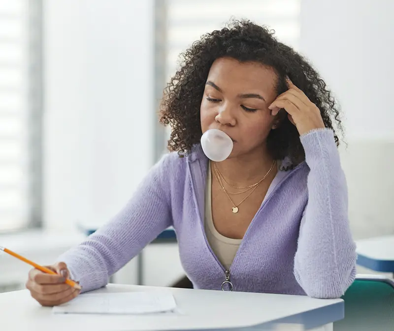 Woman blowing her bubble gum while taking her exam