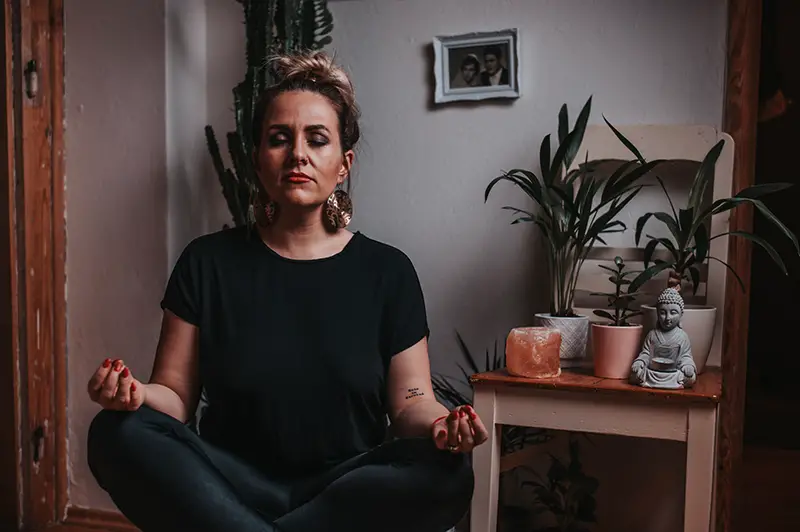 Calm woman meditating with closed eyes at home