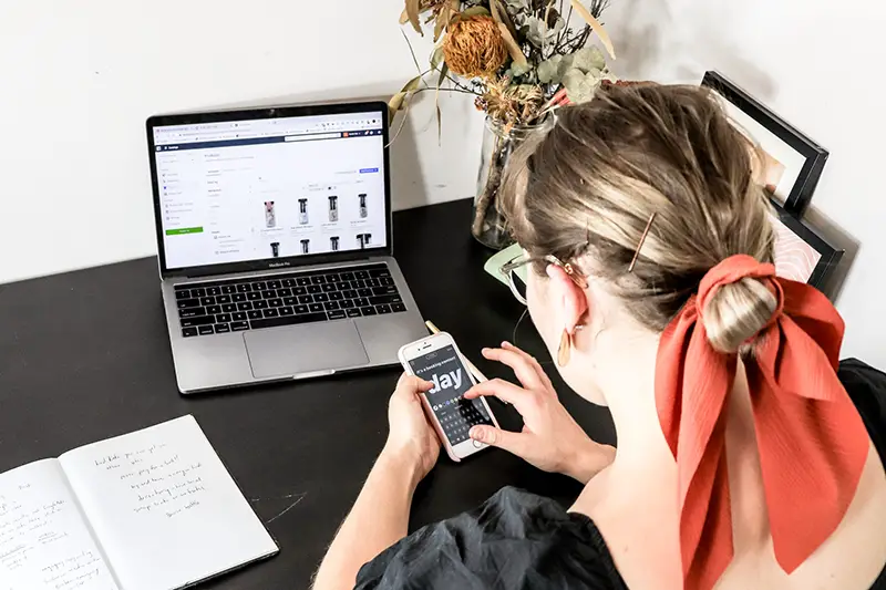 Woman using iphone in front of laptop