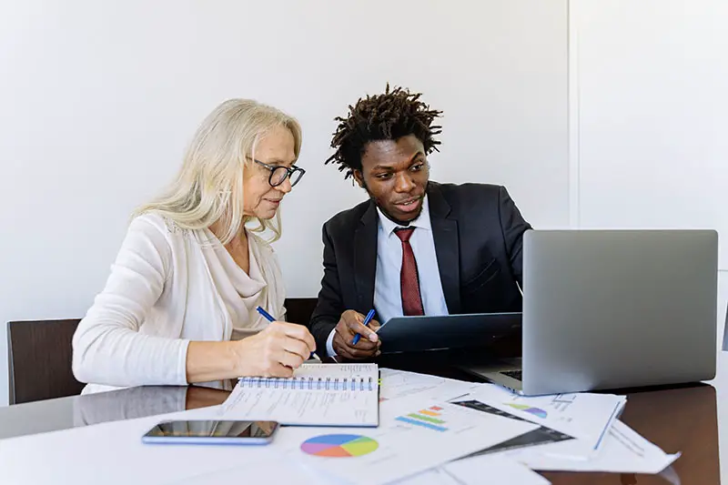 woman looking at the laptop beside a man in black suite