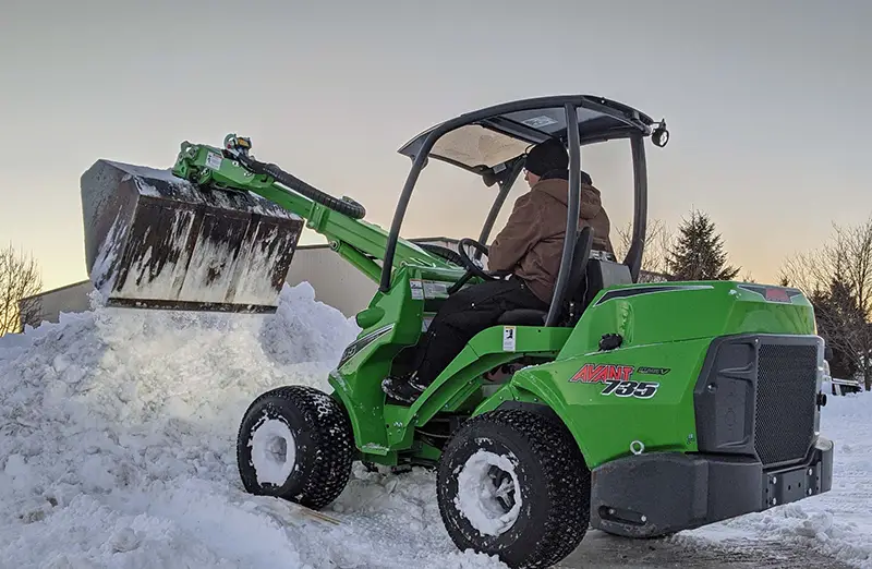 Avant Tecno Articulating Wheel Loader model 735 with bucket moving snow with a general bucket.