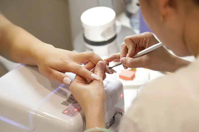 Woman putting a nail polish to a customer