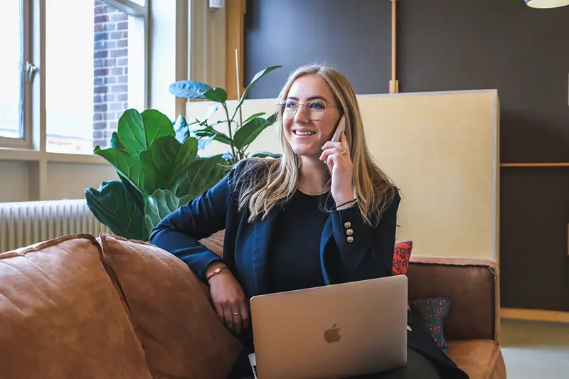 Woman in a blue coat on call while sitting in the couch