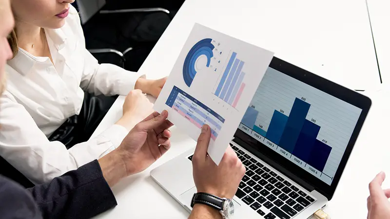 Person holding white paper near the laptop