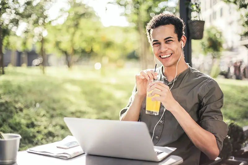 happy man sitting with laptop and juice in the park