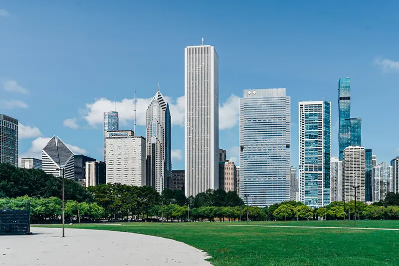 Modern city district with skyscrapers near green lawn