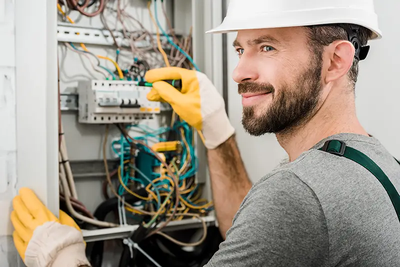 electrician repairing electrical box with pliers in corridor