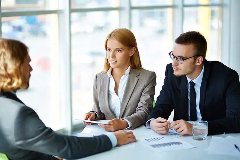 business partners listening attentively to young man at meeting in office