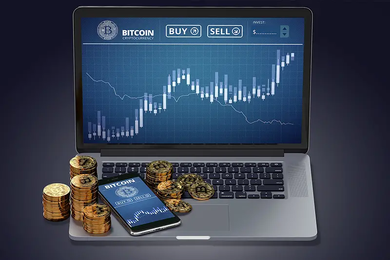 Laptop with Bitcoin chart on-screen among piles of Bitcoin