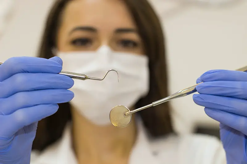 Female dentist wearing facemask and blue rubber gloves