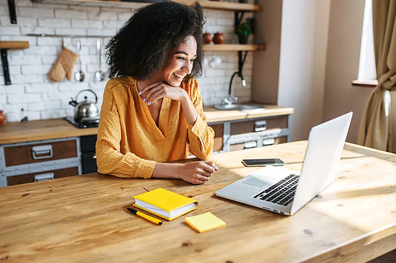 A cheerful mixed-race girl uses laptop for remote work