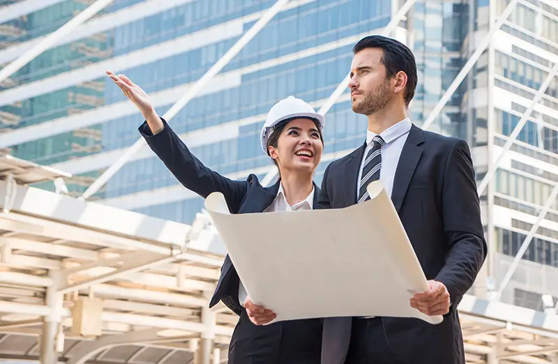 à¸ºBeautiful architect wore a suit and helmet, standing and talking to a male businessman in a real estate construction project.Estate Property Development concept.