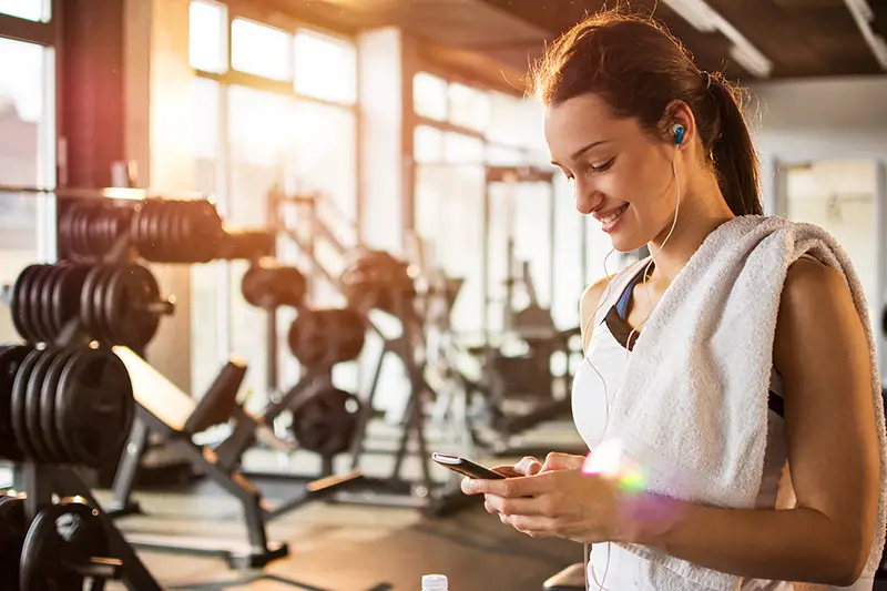 Active girl using smartphone in fitness gym