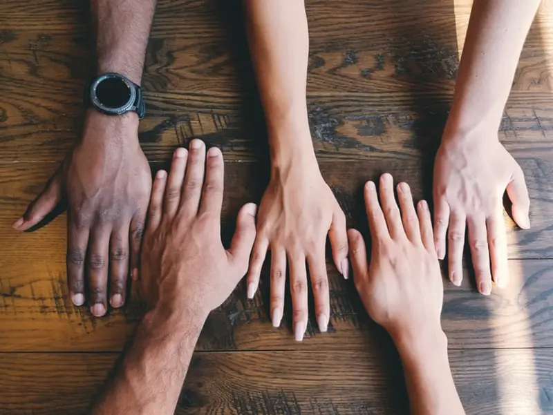 Five human hands on brown surface