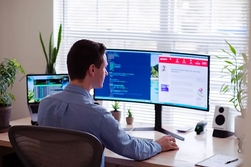 Man in gray sitting on chair in front of computer