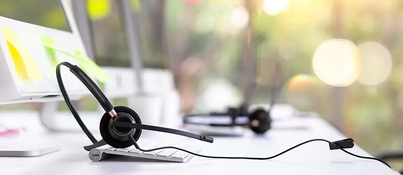 VOIP headset on desk with computer desktop at customer service and marketing support workplace.