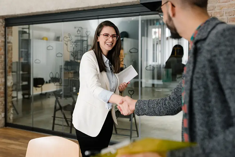 Female job recruiter firm handshaking to a male applicant