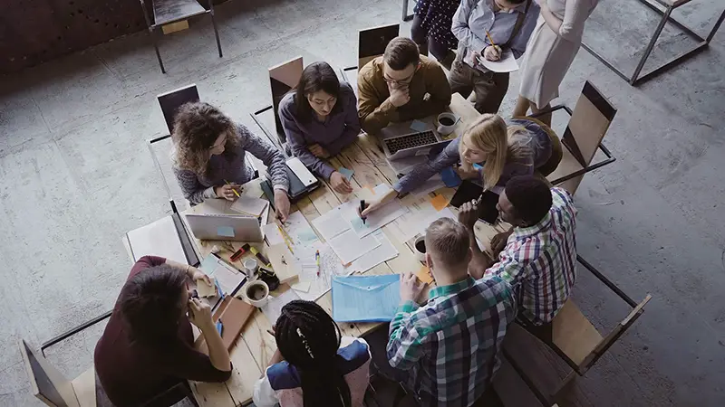 Top view of mixed race business team sitting at the table at loft office