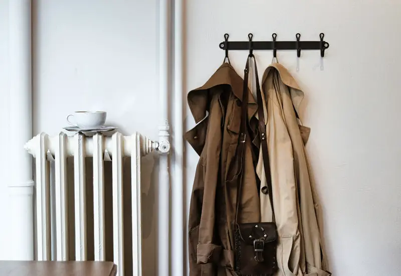 Coats and shoulder bag on hooks  near the heater