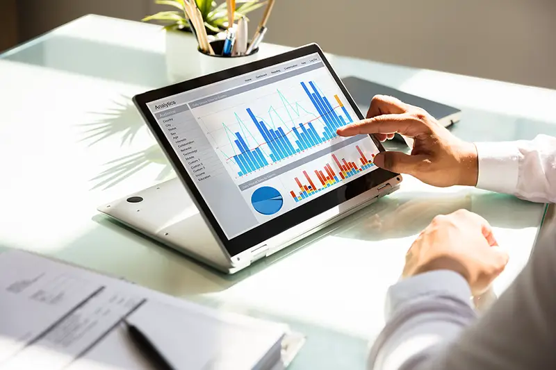 Close-up of a businessman's hand analyzing graph on laptop