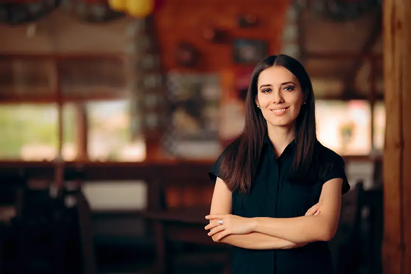 Manager Standing in a Restaurant Welcoming Customers.