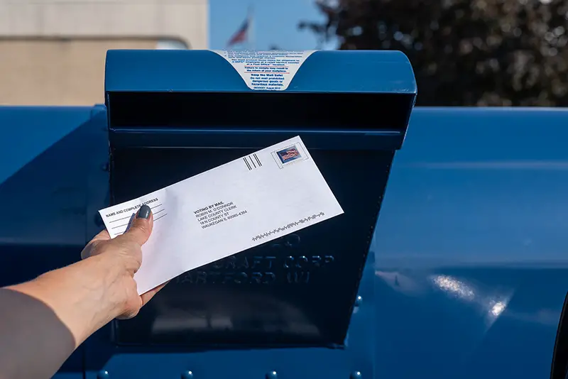 Person putting an envelope to a mail box