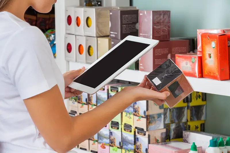 Midsection of young woman scanning barcode through digital tablet at supermarket