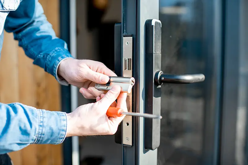 Man changing core of a door lock of the entrance glass door