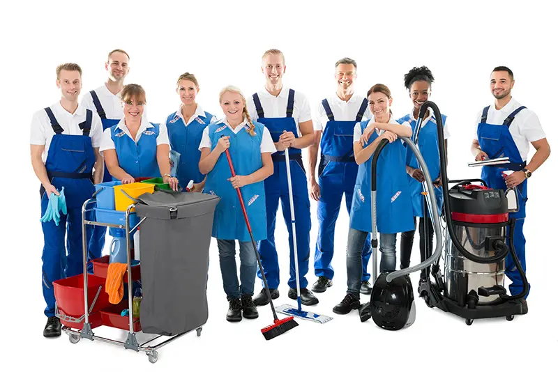 Portrait of happy janitors with cleaning equipment standing against white background