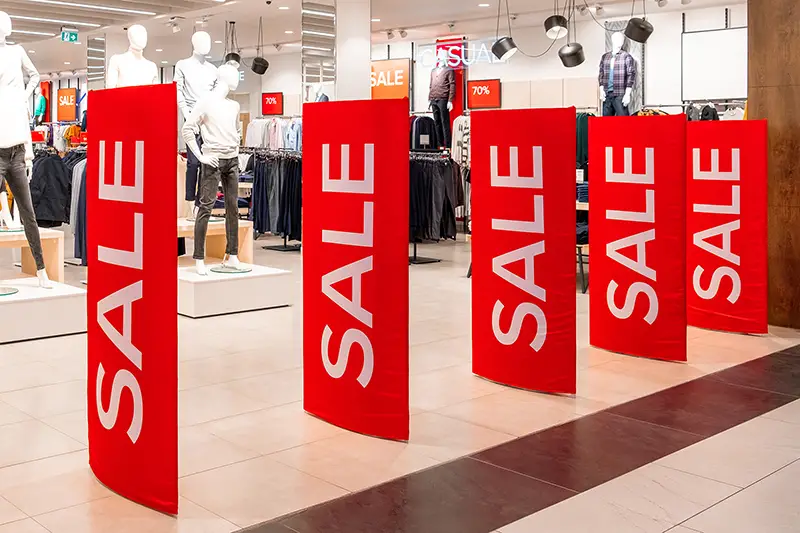 Large red panels with a sale sign at the entrance to a clothing store. 