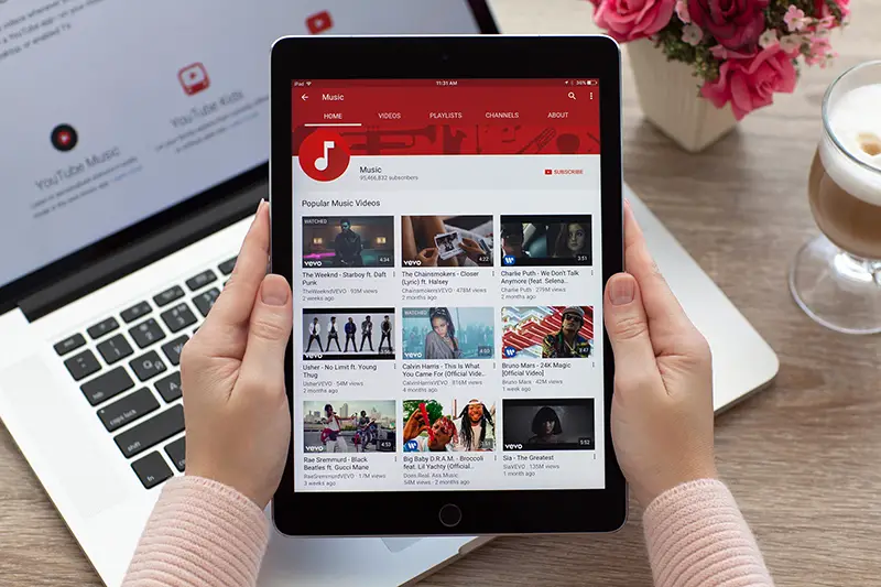 Woman holding a iPad Pro Space Gray with video sharing website YouTube on the screen.