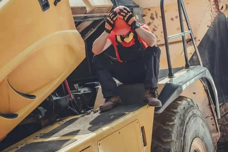 Tractor driver sitting while his two hands on his head