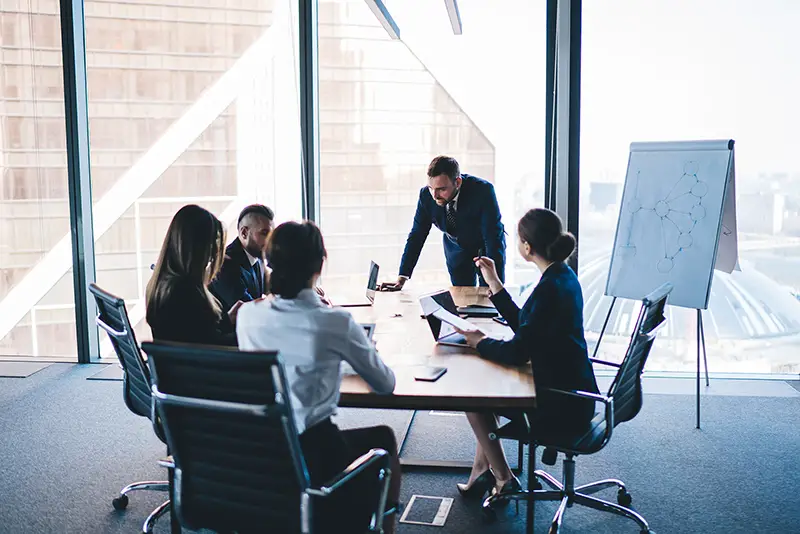 Group of coworkers in formal wear sitting at table in conference room