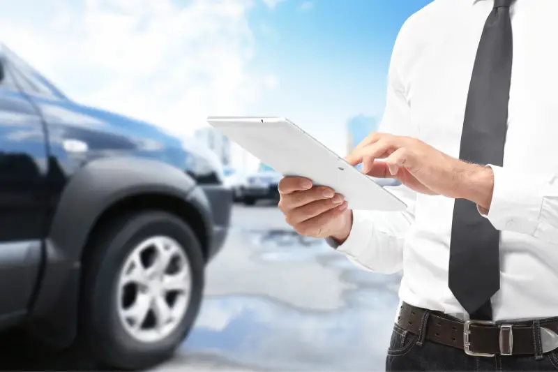 Insurance agent using tablet and car on background